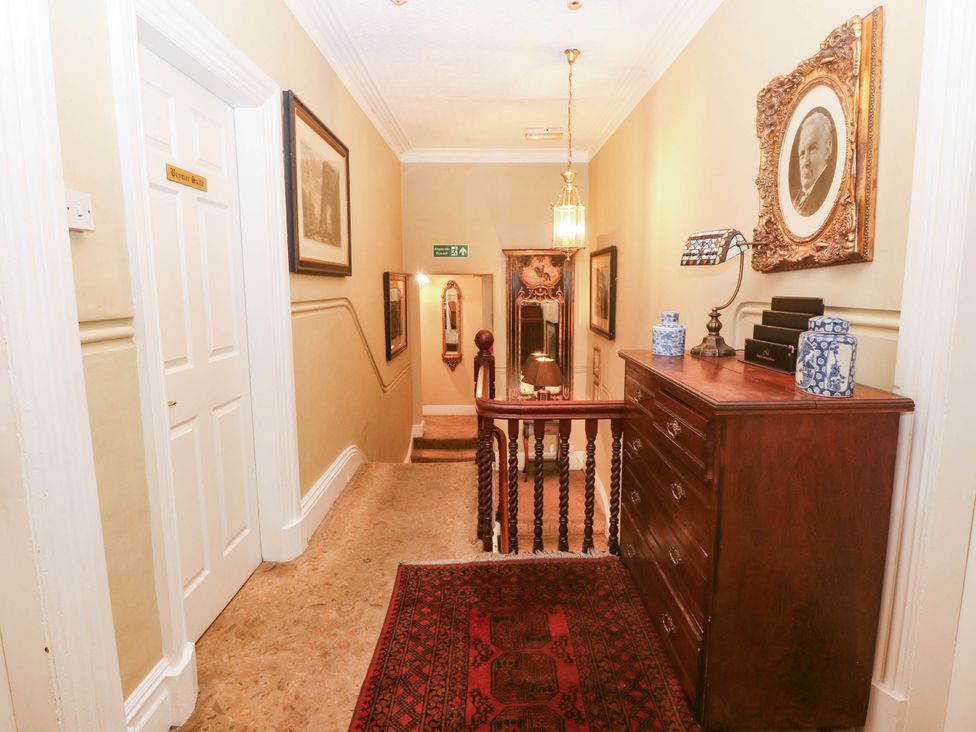A hallway with a staircase and decorative items at Meifod Country House Caernarfon