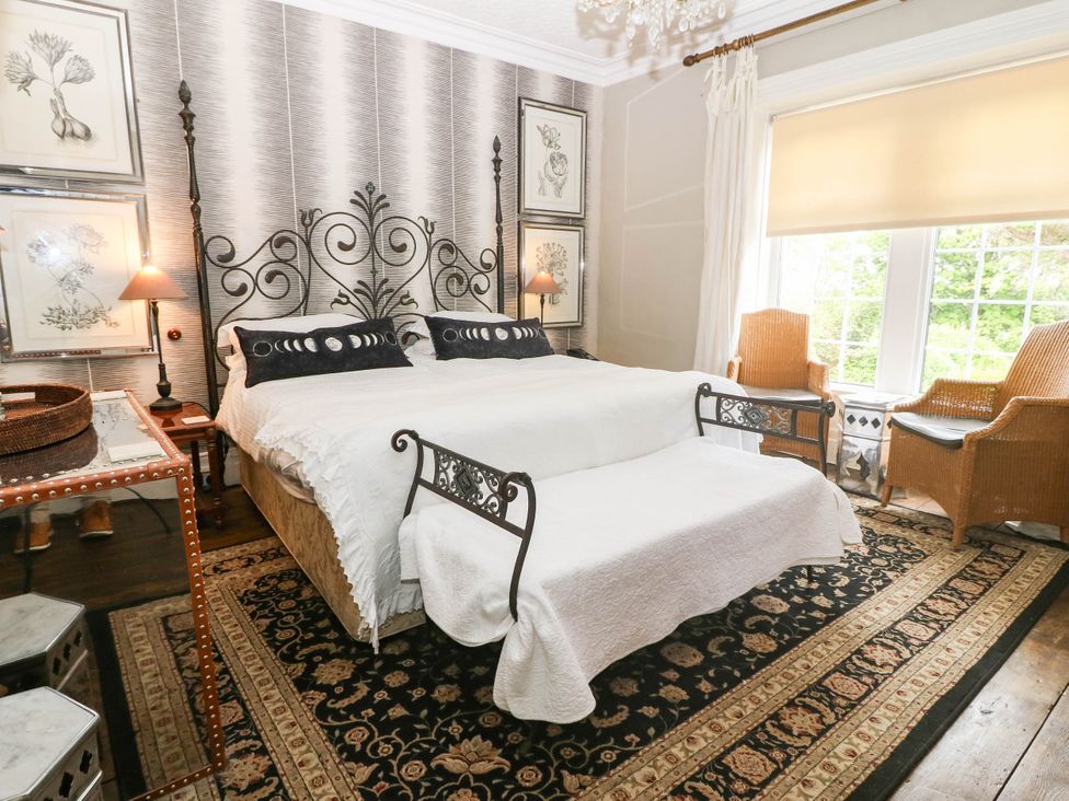 A bedroom with a large bed and armchairs at Meifod Country House in Caernarfon