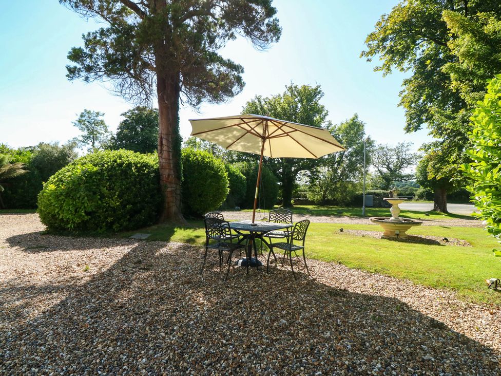 A garden area with a table and chairs under an umbrella at Meifod Country House in Caernarfon