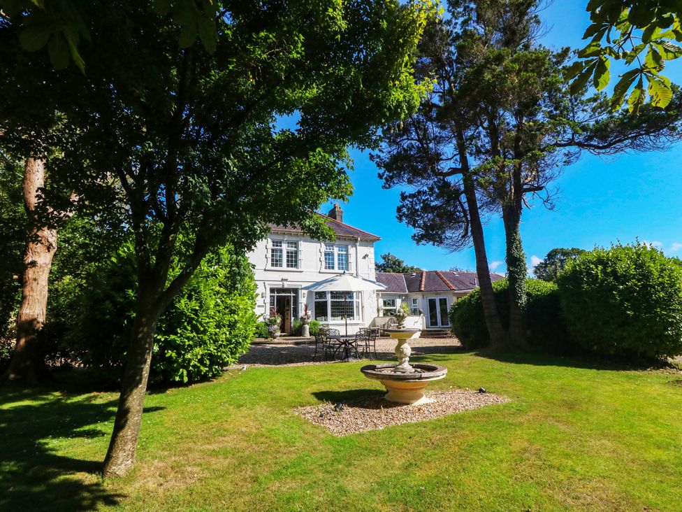 An outdoor area with a house, garden, and fountain at Meifod Country House, Caernarfon