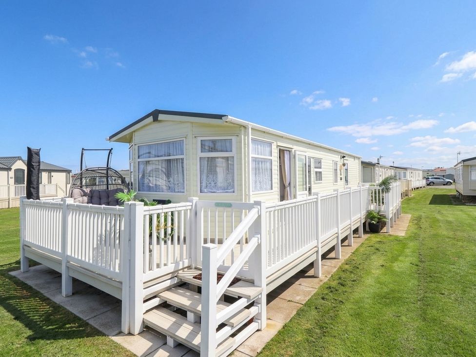 A mobile home with a deck and hammock chair at Atlas in Ingoldmells