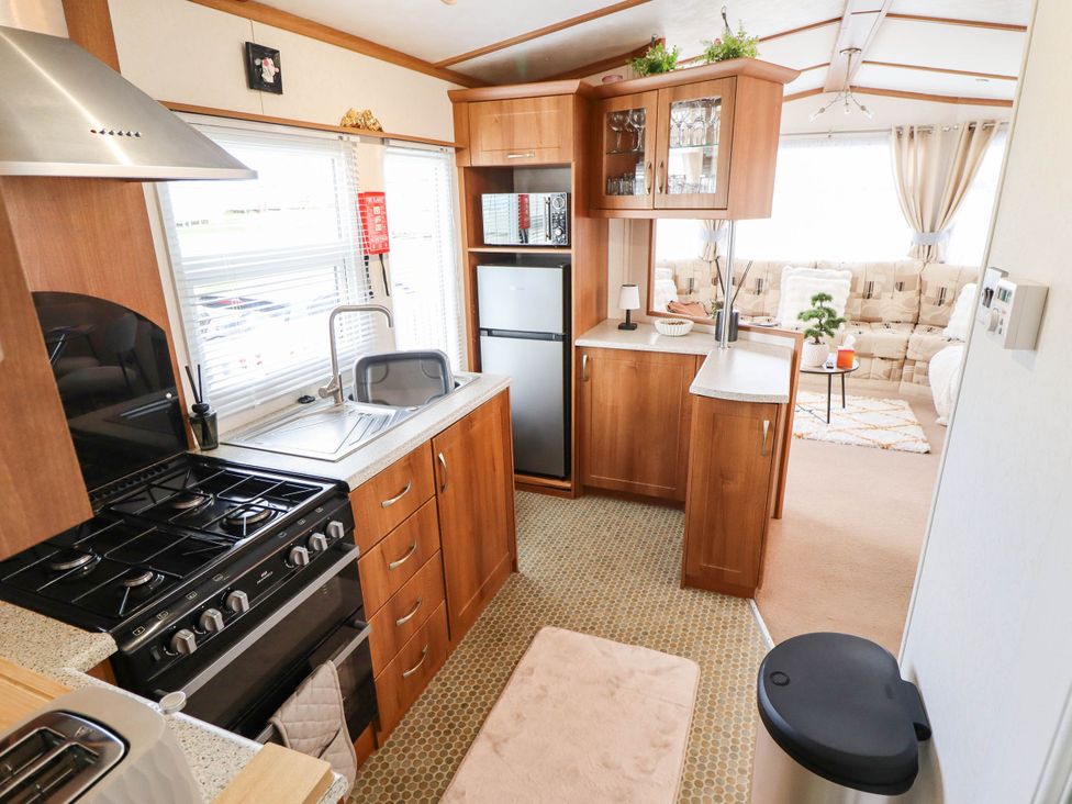 A kitchen with wooden cabinets and appliances at Atlas in Ingoldmells