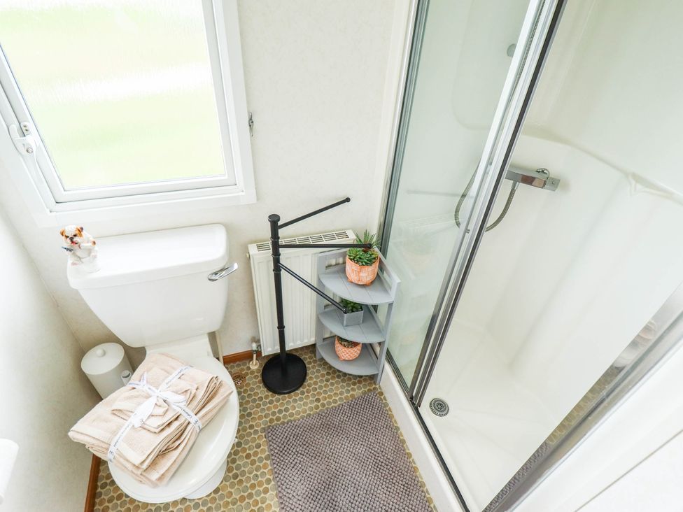A bathroom with a toilet, shower, and towels at Atlas in Ingoldmells