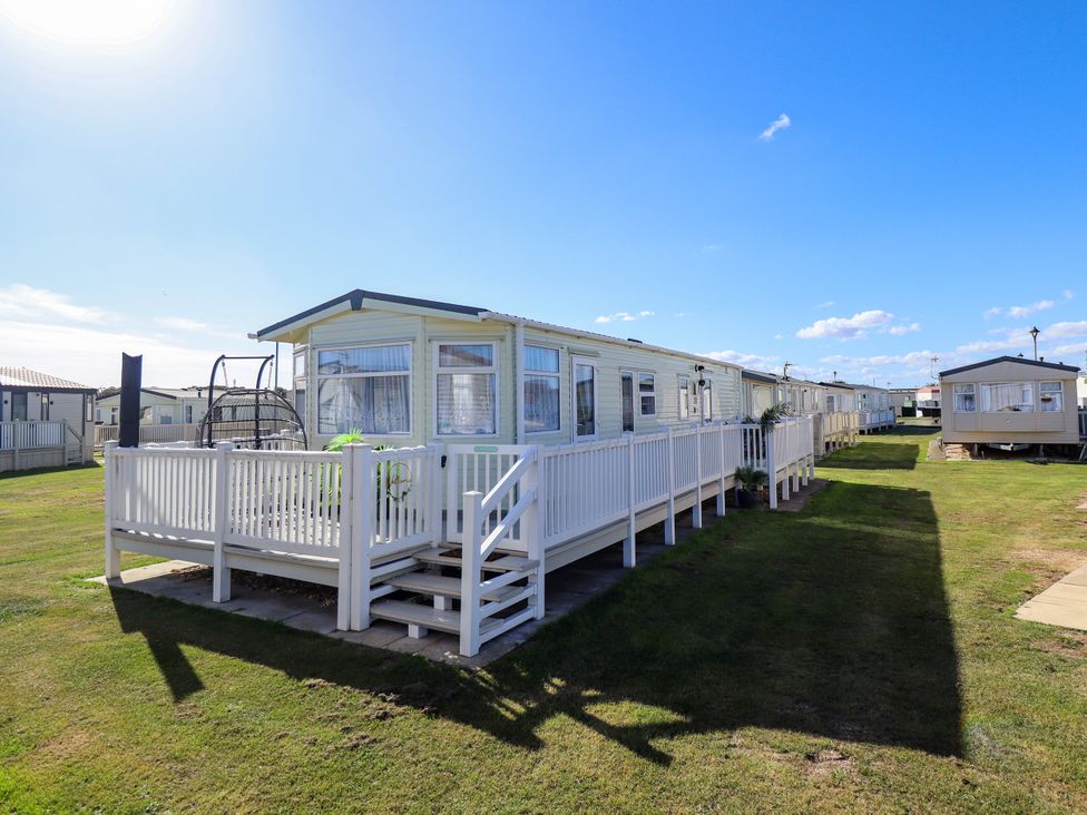 A caravan with a deck and hanging chair at Atlas in Ingoldmells