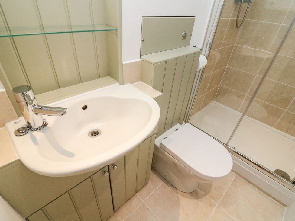 A bathroom with a washbasin, toilet, and shower at Crag Cottage in Settle