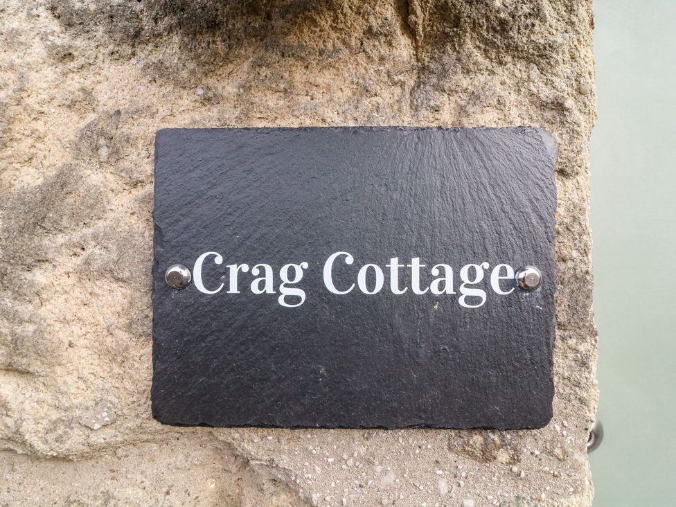 A slate sign reading Crag Cottage