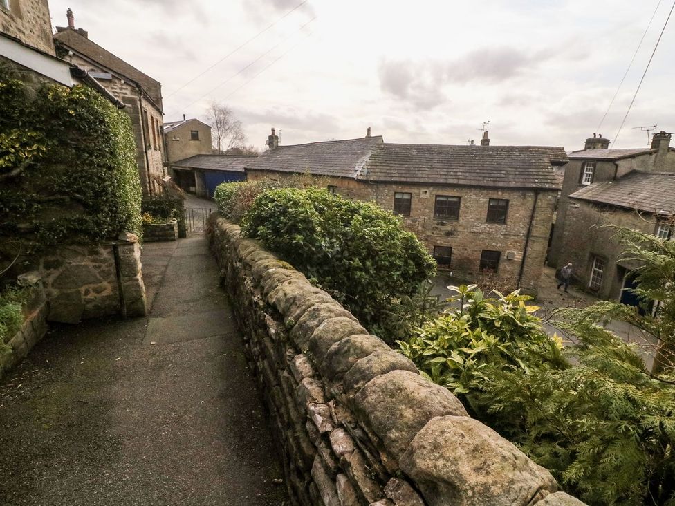 A pathway lined with a stone wall and buildings in the background at Crag Cottage, Settle