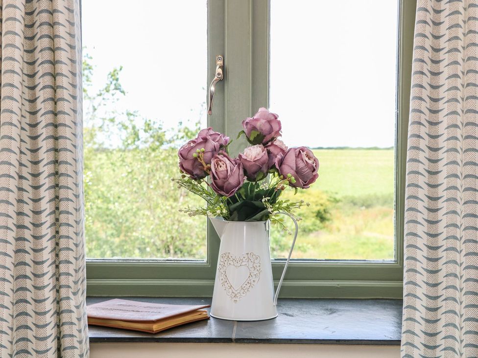 A window with a flower vase and book at Beech Cottage in Truro