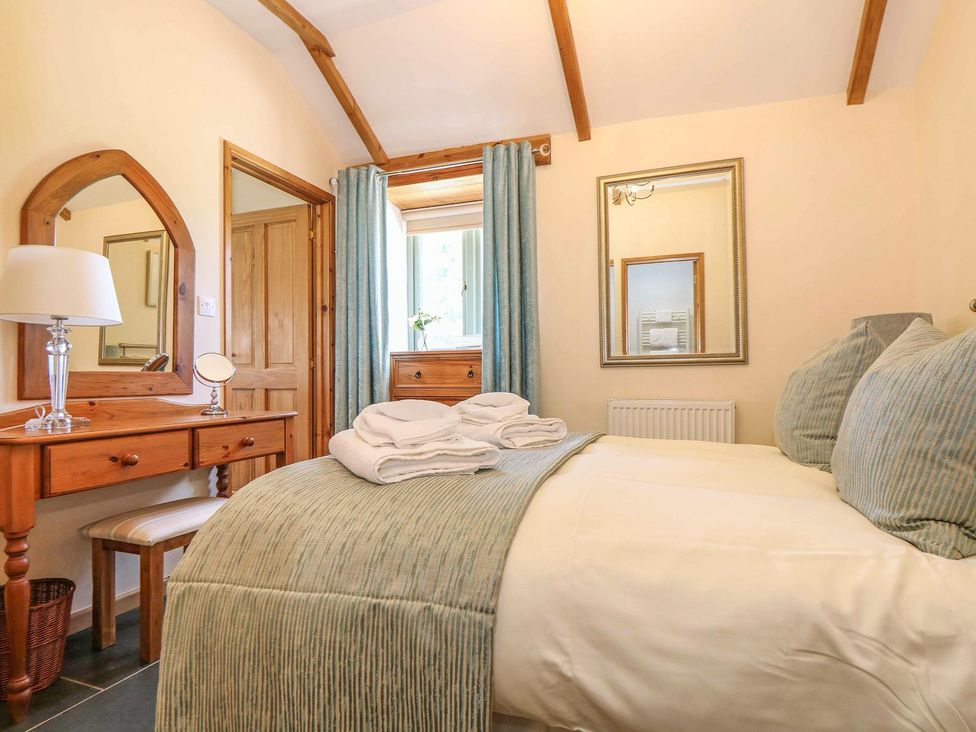 A bedroom with a bed and a mirror at Beech Cottage in Truro