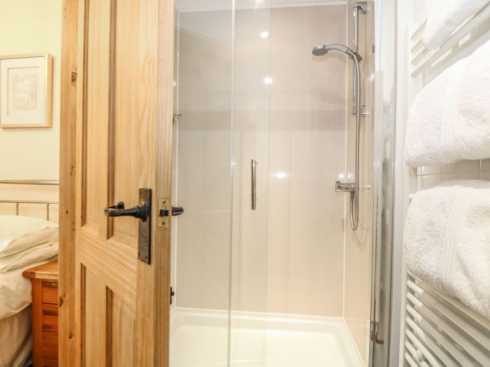 A shower with towels and a wooden door at Beech Cottage in Truro