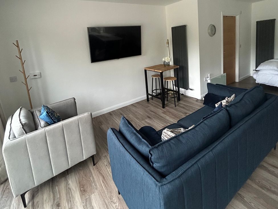 A living room with a sofa, armchair, table, and television at Broomfield Hideaway near Inverness