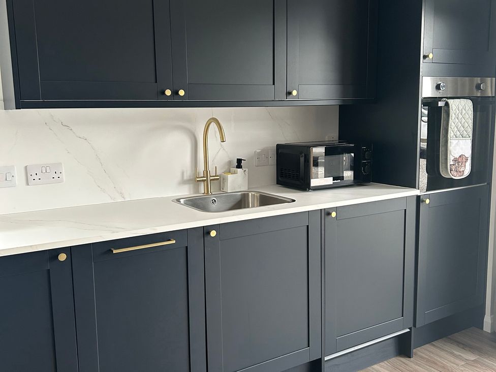 A kitchen with cabinets, sink, tap, and microwave at Broomfield Hideaway near Inverness