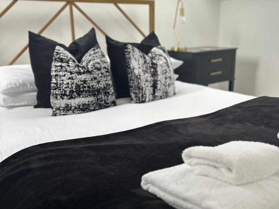 A bed with black and white pillows and towels at Broomfield Hideaway near Inverness