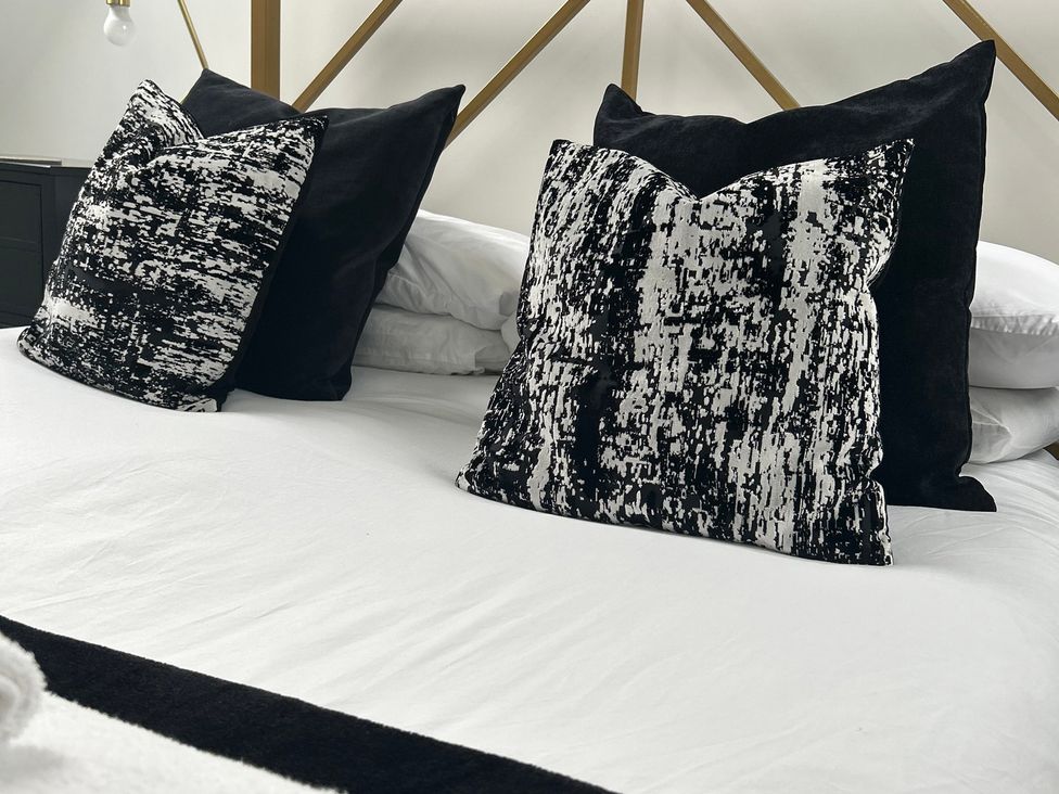 A bed with black and white pillows at Broomfield Hideaway near Inverness