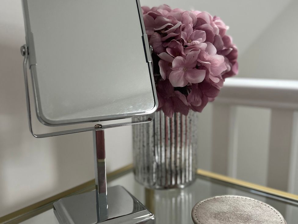 A mirror and a vase of flowers on a table at Broomfield Hideaway near Inverness
