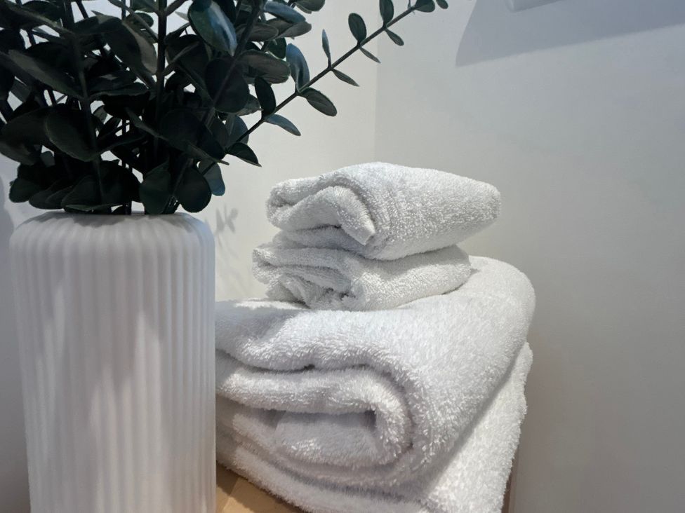 A stack of white towels next to a potted plant at Broomfield Hideaway near Inverness