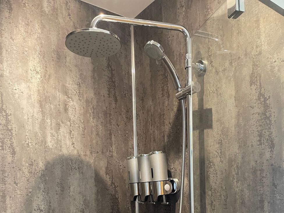 A shower with a wall-mounted showerhead and handheld shower at Broomfield Hideaway near Inverness