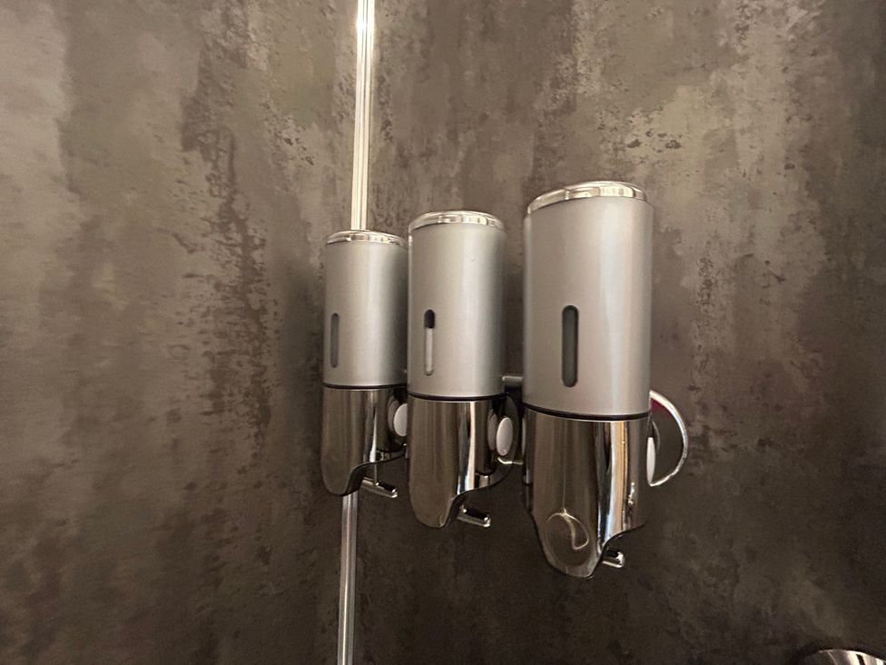 A shower area with three dispensers at Broomfield Hideaway near Inverness