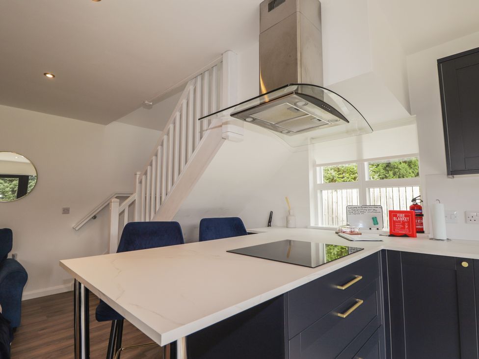 A kitchen with a kitchen island and a staircase at Broomfield Hideaway near Inverness
