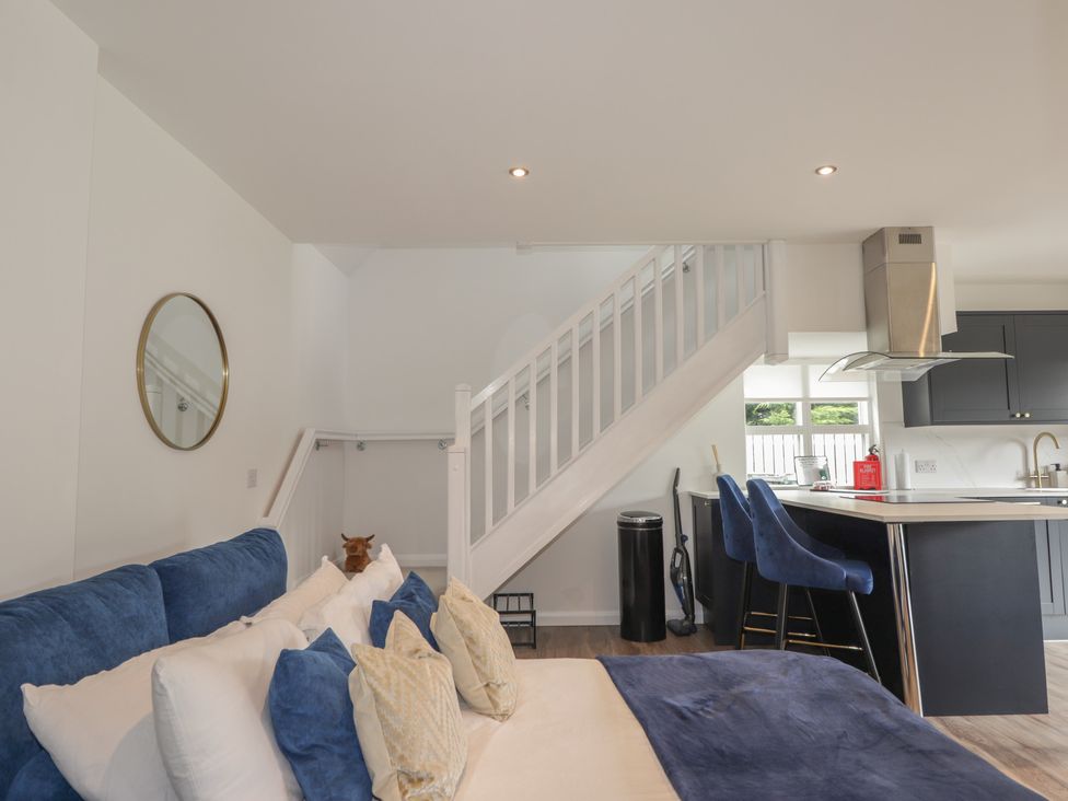 A living room with a staircase and a kitchen area at Broomfield Hideaway near Inverness