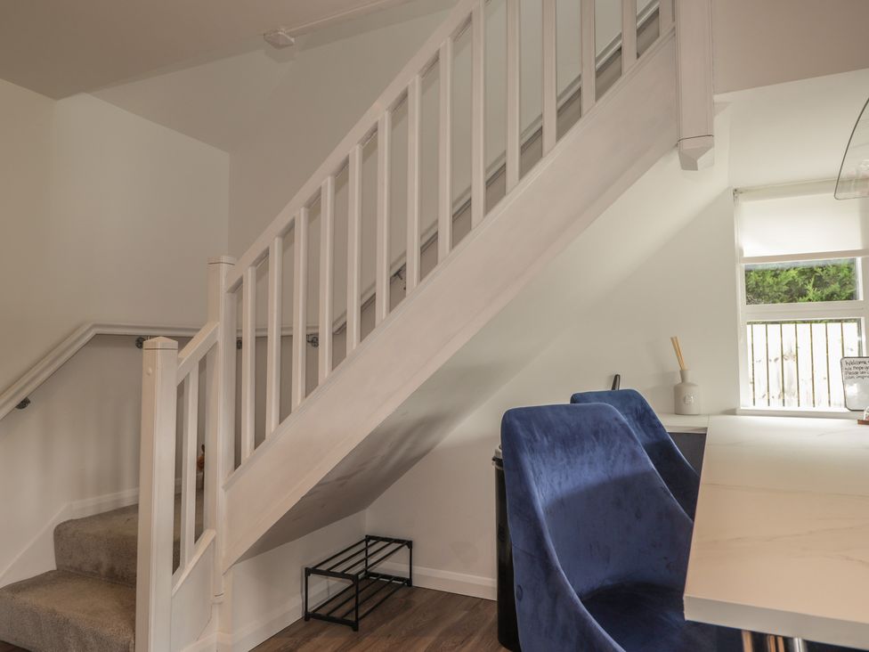 A living room with a staircase and a table and chair at Broomfield Hideaway near Inverness