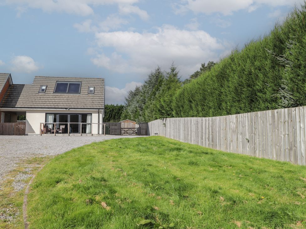 A house with a gravel driveway and green grass at Broomfield Hideaway near Inverness