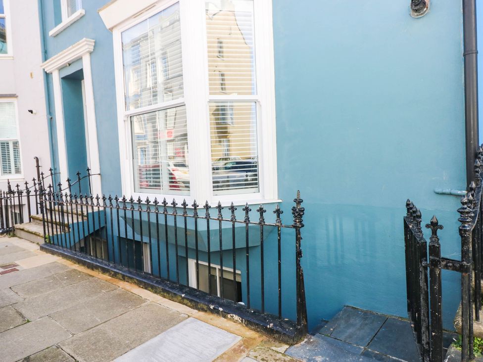 An outdoor view of a building facade with a window and railings at the Basement Apartment in Tenby