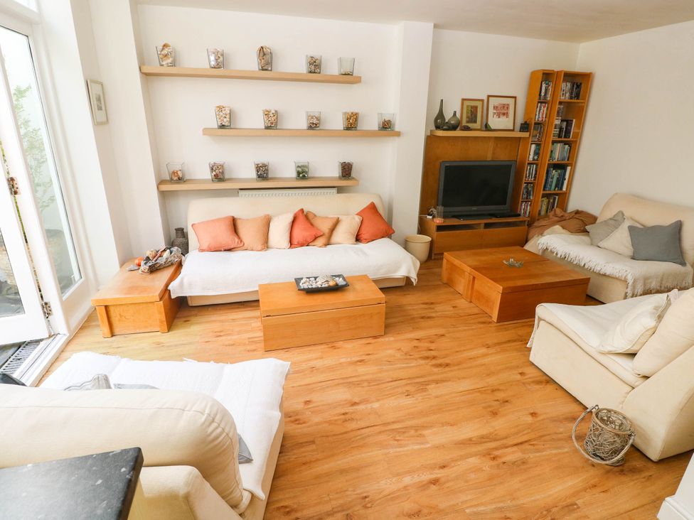 A living room with a sofa, coffee table, and television at Basement Apartment in Tenby