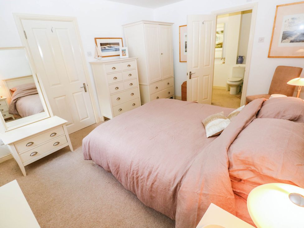 A bedroom with a bed and dresser at Basement Apartment in Tenby