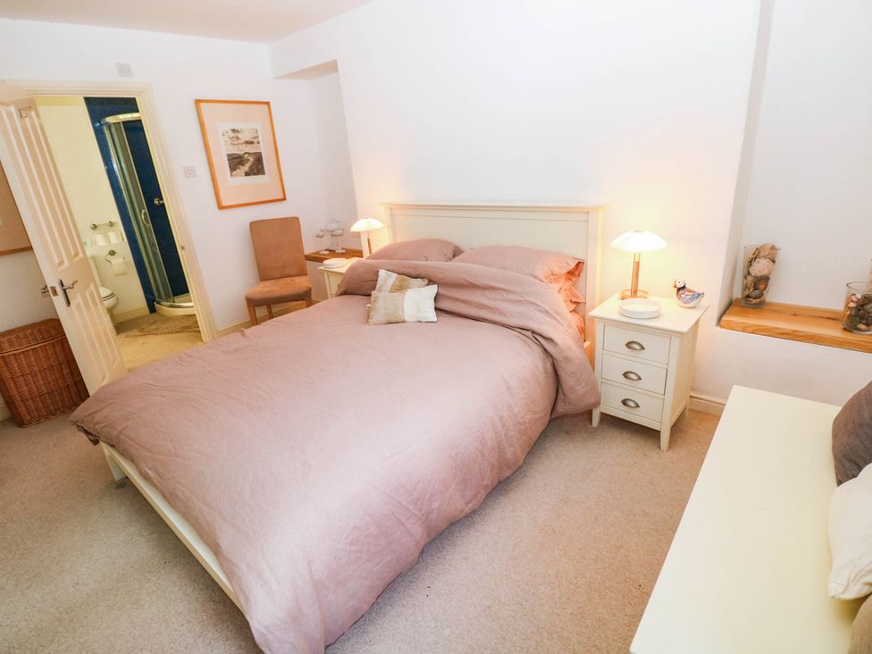 A bedroom with a bed and nightstand at Basement Apartment in Tenby