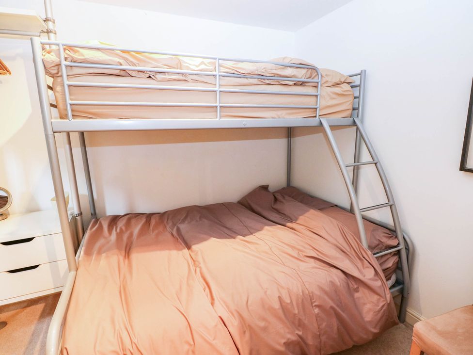 A bedroom with a bunk bed and bedding at Basement Apartment in Tenby