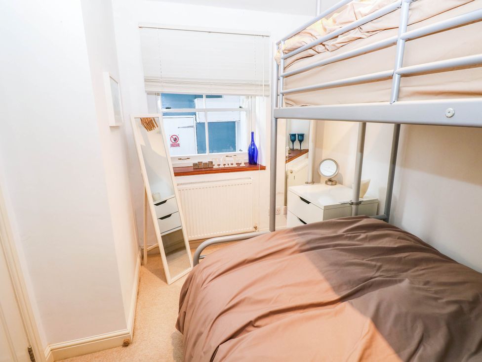 A bedroom with a bunk bed and a mirror at Basement Apartment in Tenby