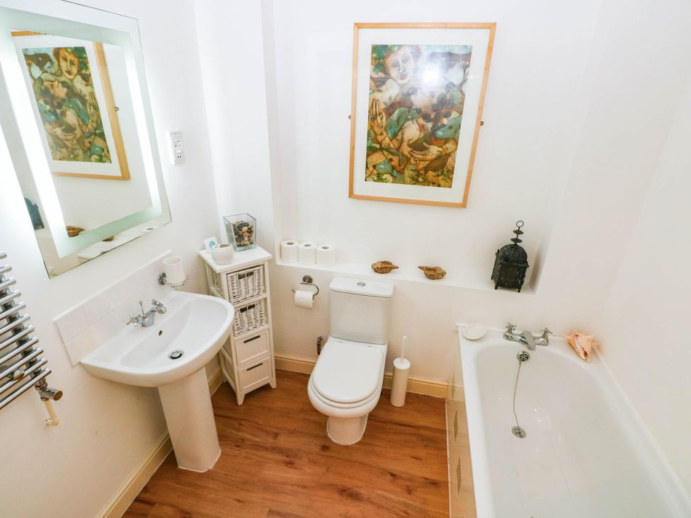 A bathroom with a sink, toilet, and bathtub at Basement Apartment in Tenby