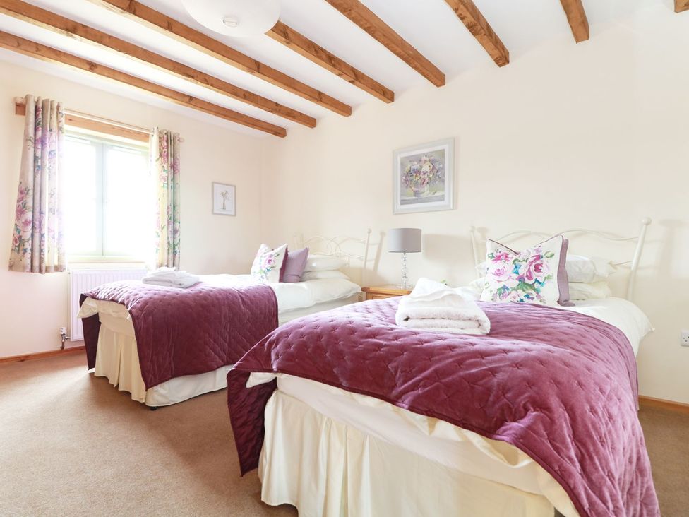 A bedroom with two beds and a window at Hawthorn Cottage in Truro