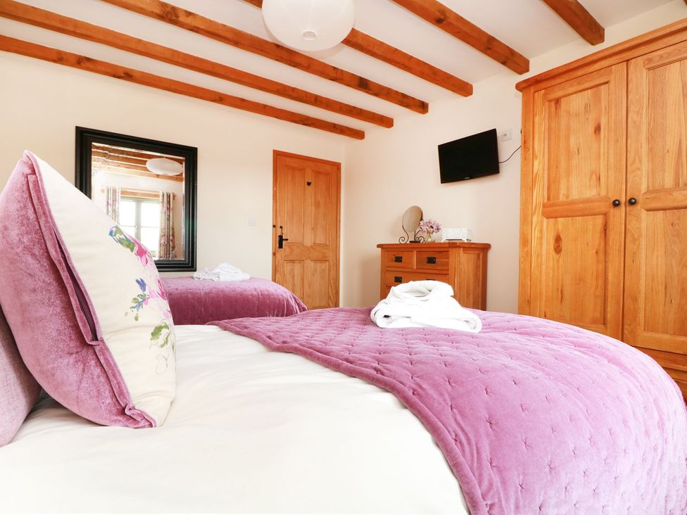 A bedroom with beds and a wardrobe at Hawthorn Cottage in Truro