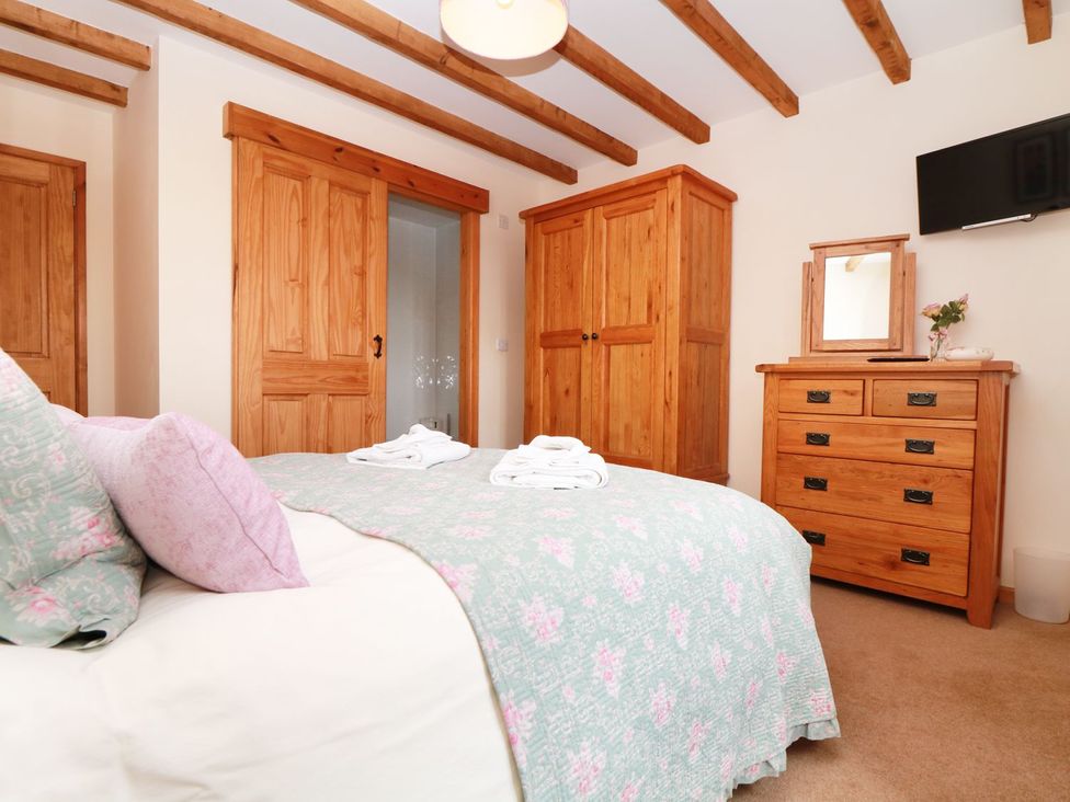 A bedroom with a bed, wardrobe, chest of drawers and a TV at Hawthorn Cottage in Truro
