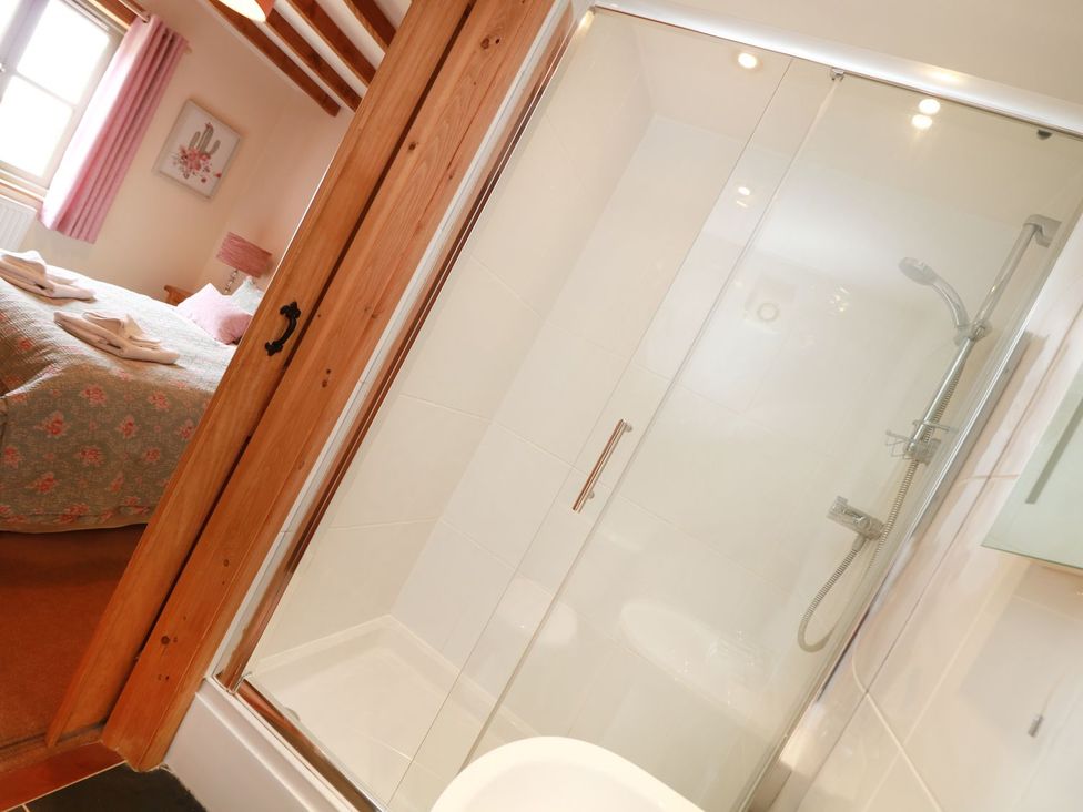 A bathroom featuring a shower and a glimpse of a bedroom at Hawthorn Cottage in Truro
