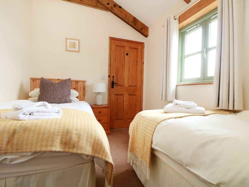 A bedroom with two beds and a window at Hawthorn Cottage in Truro