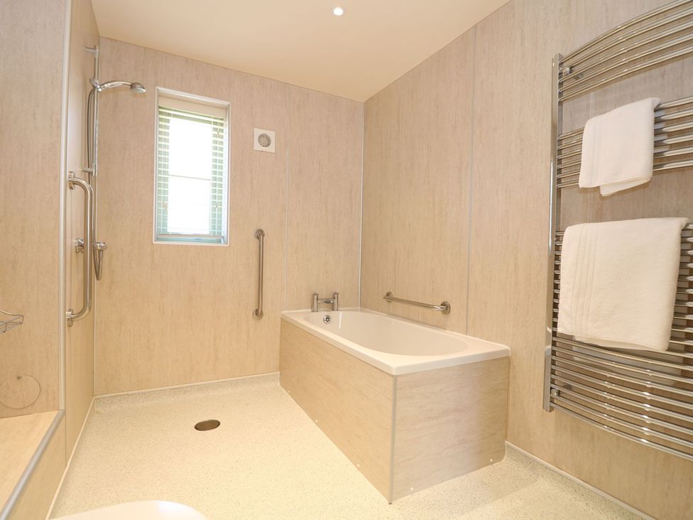 A bathroom with a bathtub and towel rack at Elm Cottage in Truro