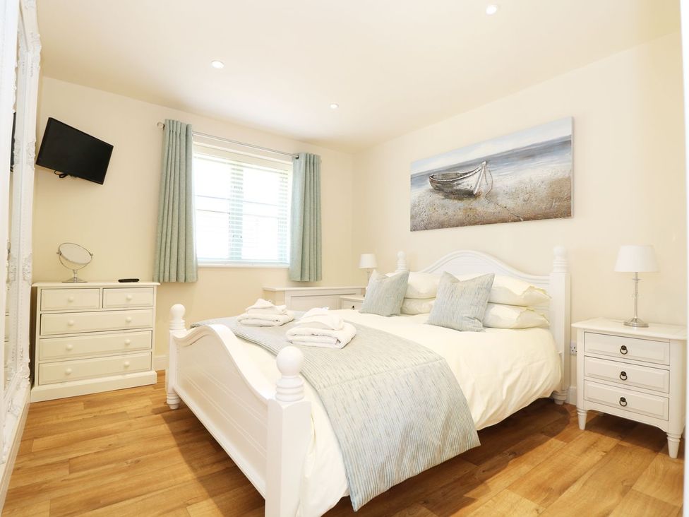 A bedroom with a bed, dresser, and television at Elm Cottage in Truro