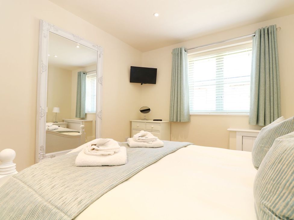 A bedroom with a bed and mirror at Elm Cottage in Truro