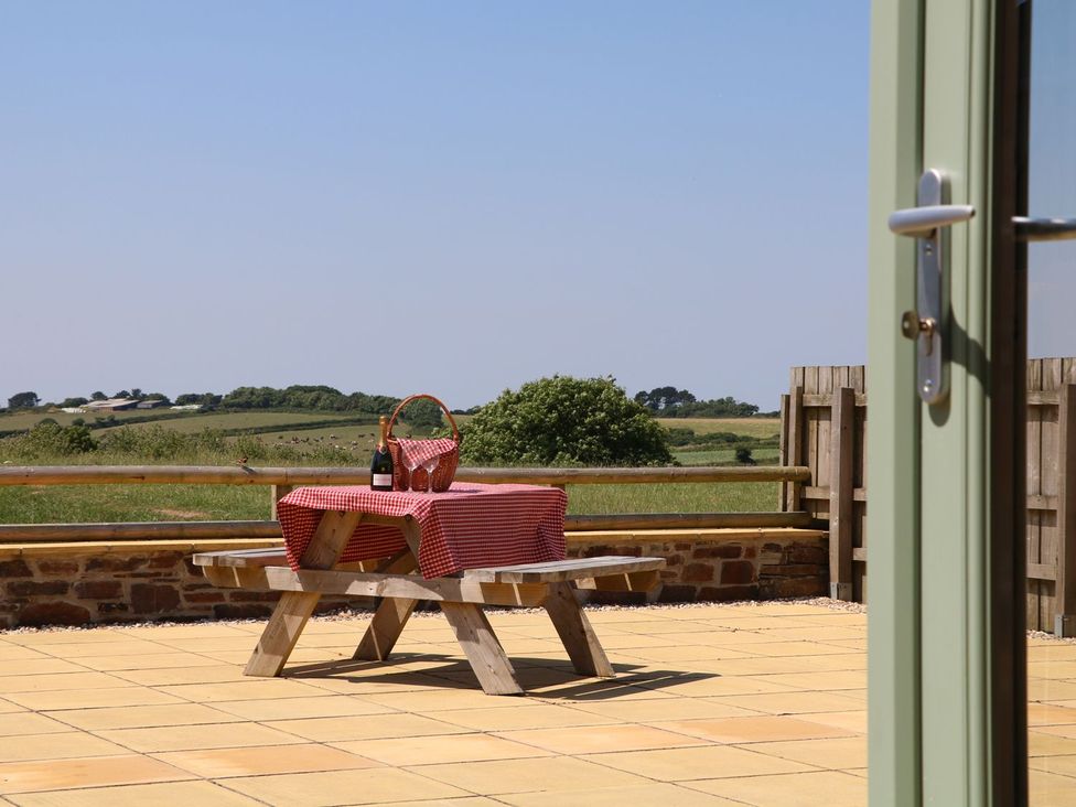 A table with a basket and wine in an outdoor area at Elm Cottage in Truro
