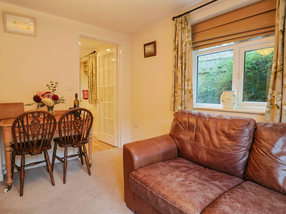A living room with a sofa and dining area at Coombe Cottage Apartment Axmouth