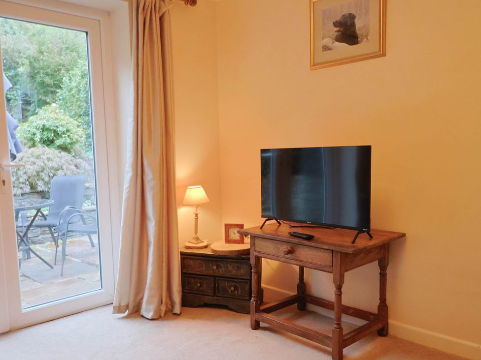 A living room with a television and a lamp at Coombe Cottage Apartment in Axmouth