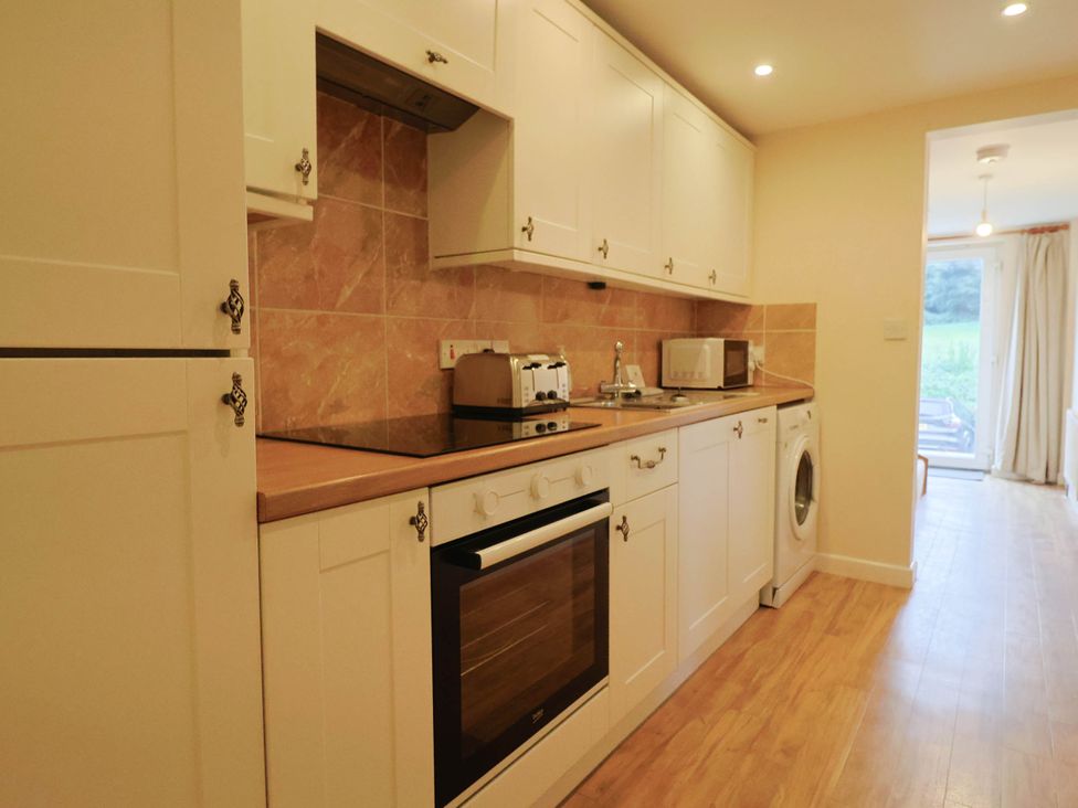 A kitchen with appliances and cabinets at Coombe Cottage Apartment in Axmouth