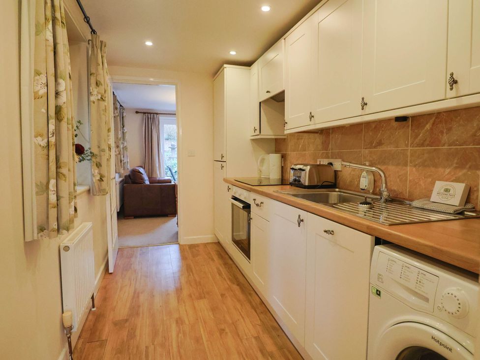 A kitchen with appliances and a window at Coombe Cottage Apartment in Axmouth
