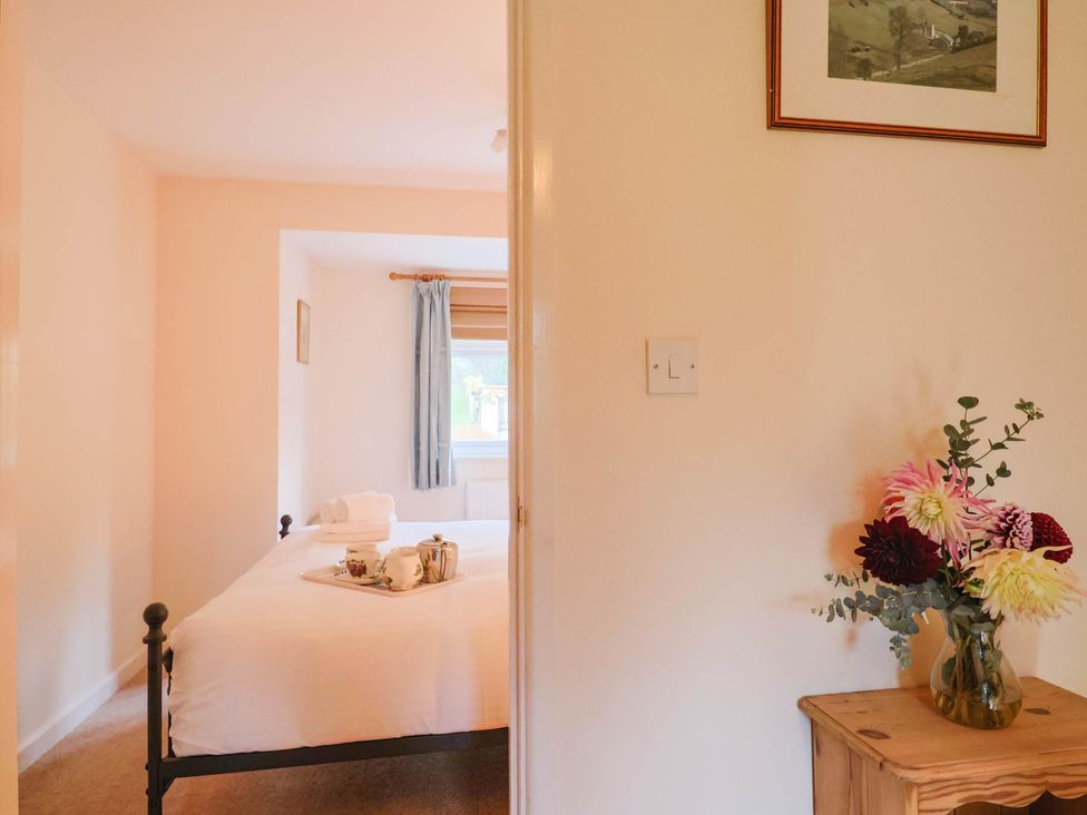 A bedroom with a bed and table at Coombe Cottage Apartment Axmouth