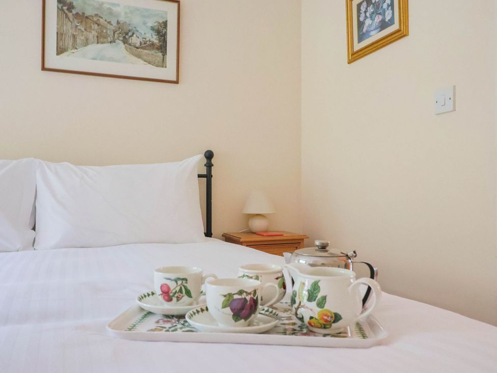 A bedroom with a tray of tea on the bed at Coombe Cottage Apartment in Axmouth