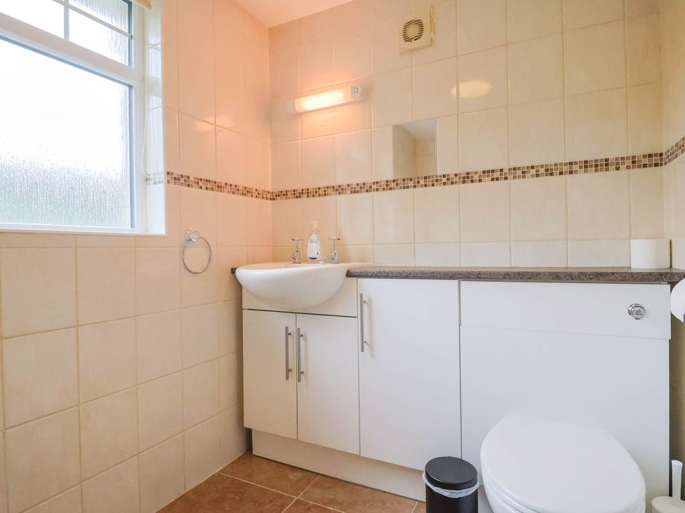 A bathroom with a sink, toilet, and window at Coombe Cottage Apartment Axmouth