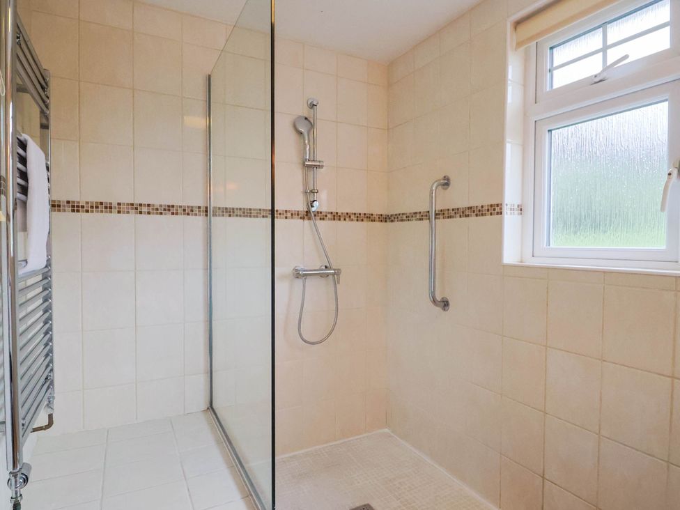 A shower with glass panel and towel rail at Coombe Cottage Apartment in Axmouth